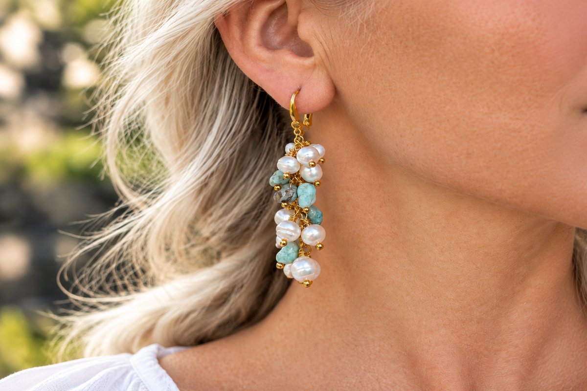 Woman wearing modern cluster drop earrings with white freshwater baroque pearls and turquoise nuggets on gold wire — contemporary pearl earrings styled for everyday wear