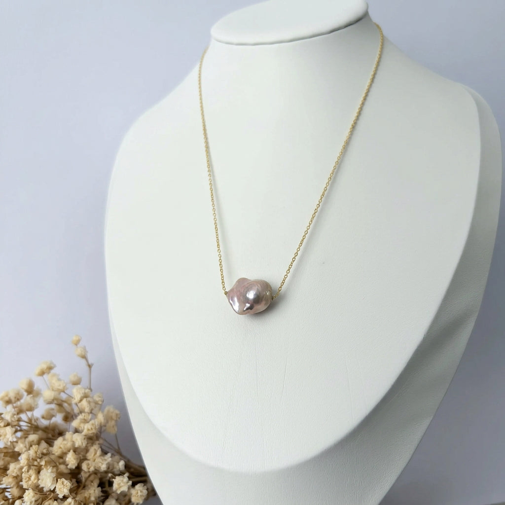 Silvery-blush keshi pearl on a fine gold-over-sterling-silver chain, displayed on a white jewellery bust beside dried cream flowers.