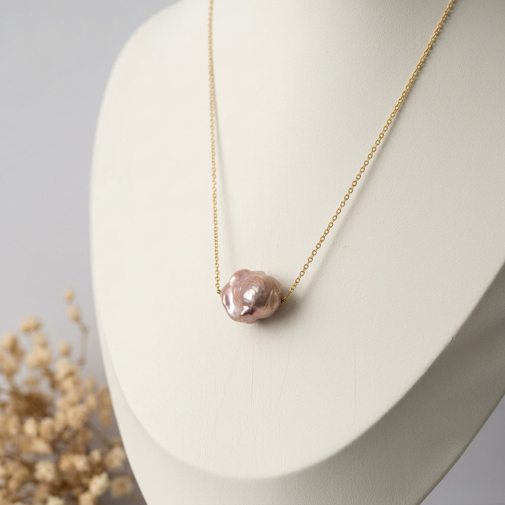 Pink Keshi pearl necklace on a fine gold-filled chain displayed on a white jewellery bust, with dried cream flowers beside the display.