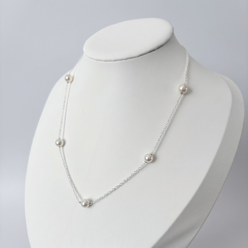 Five white Akoya pearls evenly spaced along a fine sterling silver chain, displayed on an angled white jewellery bust.