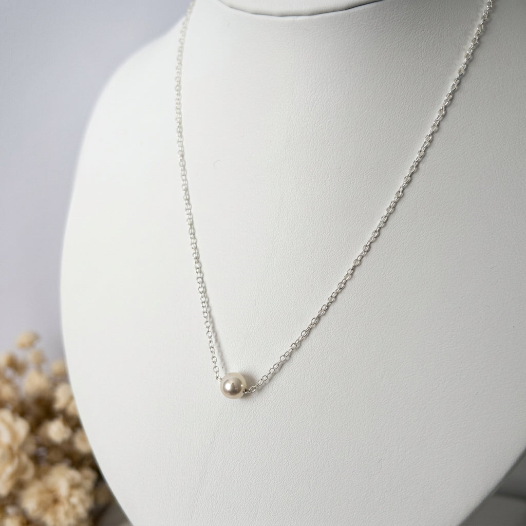 Single white Akoya pearl necklace worn at the collarbone, showing a small round pearl with bright lustre set directly on a fine sterling silver chain.