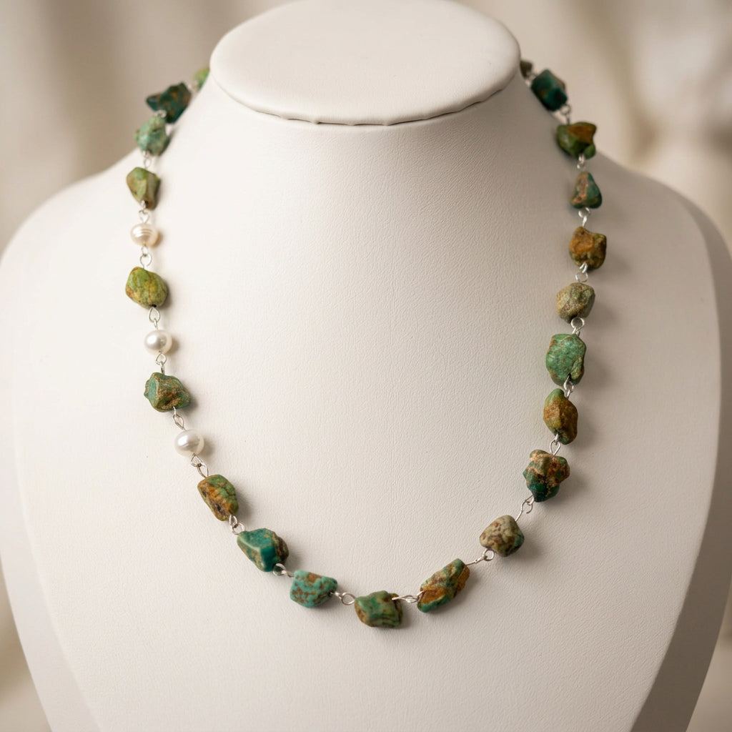 Raw Hubei turquoise necklace displayed on a white bust, showing irregular green-blue stones with earthy brown matrix, three white baroque pearls along one side and handmade sterling silver wire links.