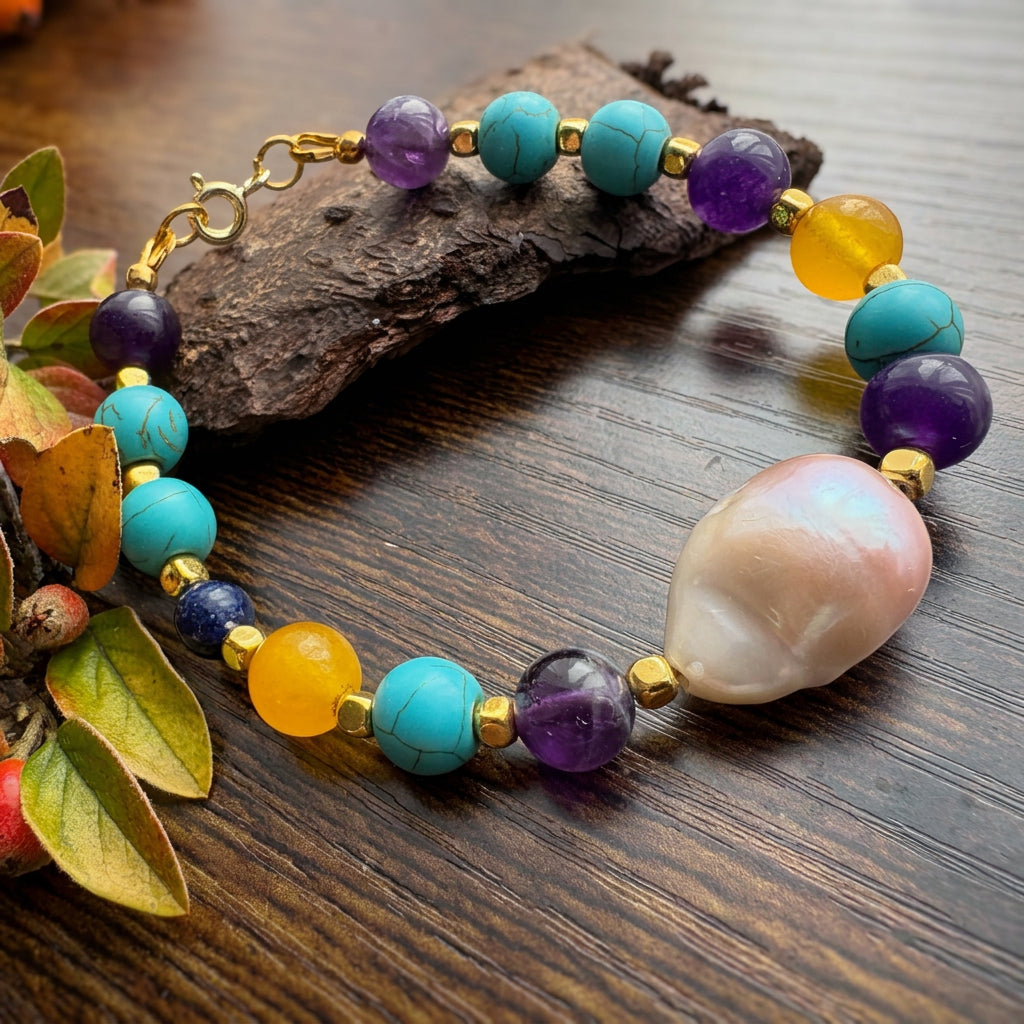 Blush-pink keshi pearl bracelet with purple amethyst, teal-blue howlite, amber-yellow topaz and gold-plated spacers, arranged on a wooden surface beside bark and autumn leaves.