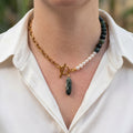 Green obsidian and white rice pearl necklace with a gold-plated paperclip chain, fastened front toggle and elongated green Indian agate pendant, worn with an open-neck white shirt.