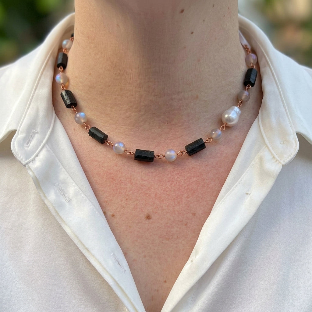 Raw black tourmaline, labradorite and silver keshi pearl necklace worn with an open-neck white shirt, showing rough black crystals, pale grey beads with blue flashes and irregular lustrous pearls joined by handmade copper wire links.