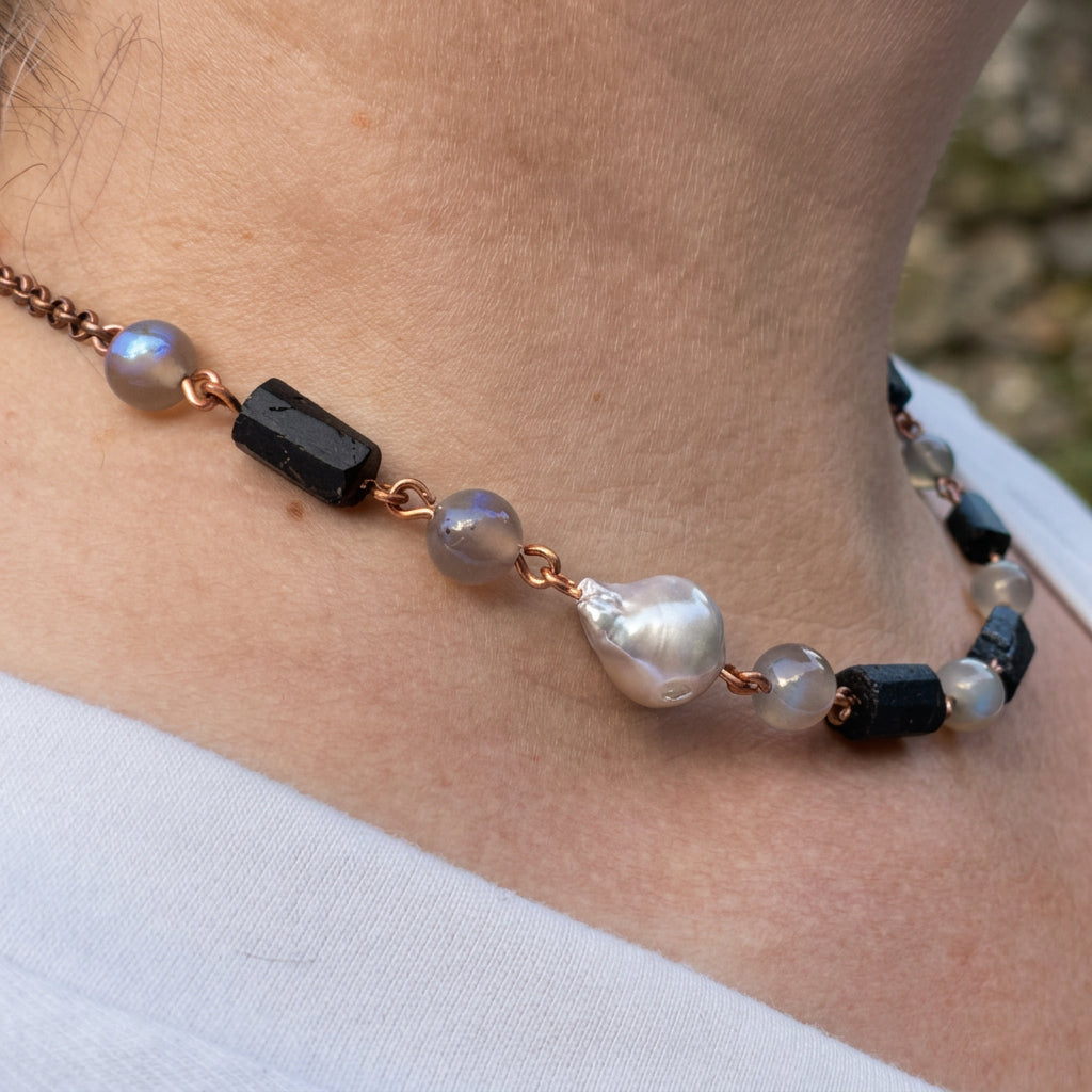 Side view of a copper wire necklace worn at the collarbone, showing a silver Keshi pearl, raw black tourmaline crystals and grey labradorite beads with blue flashes.
