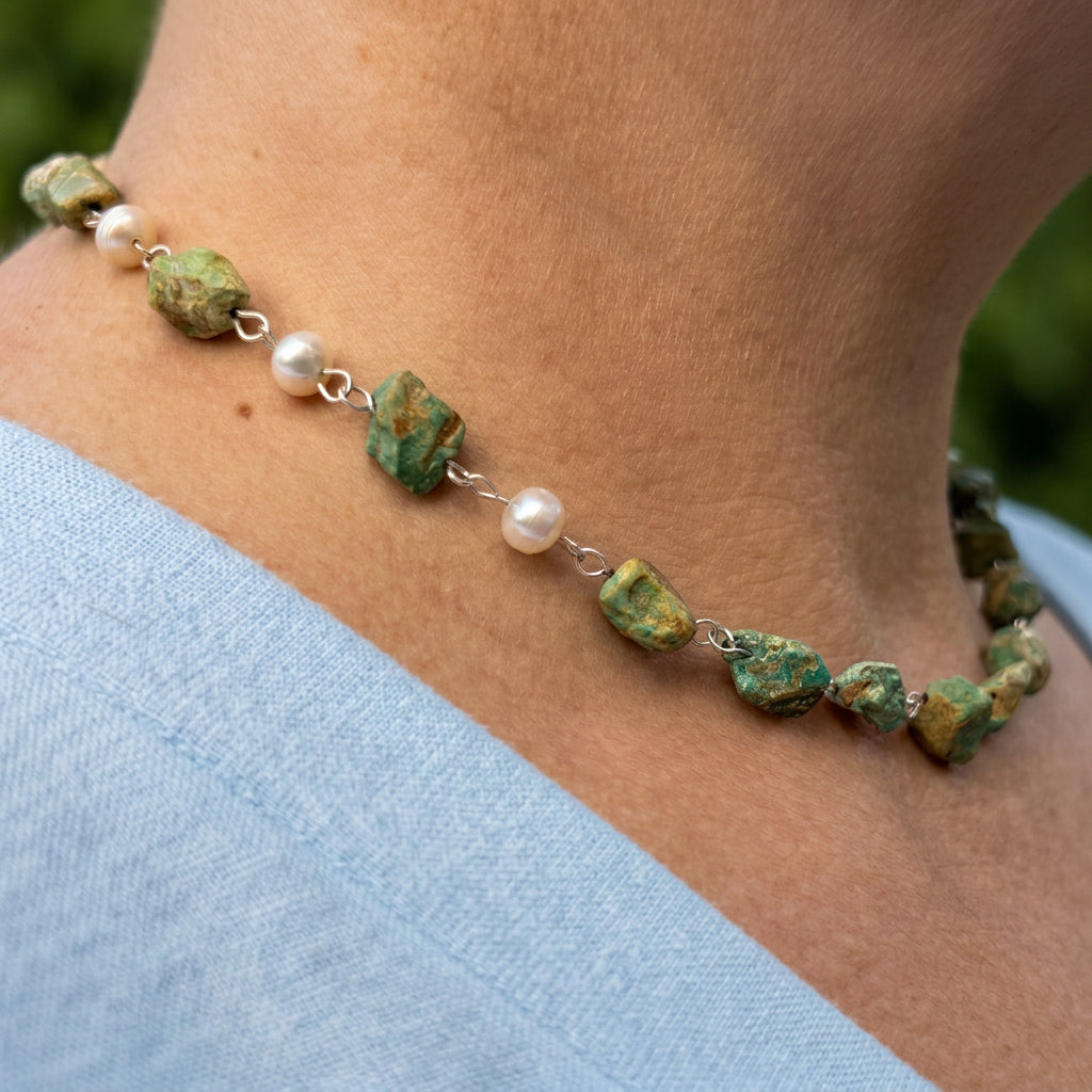 Side view of a raw Hubei turquoise necklace worn at the collarbone, showing three white baroque pearls interspersed along one side, textured green-blue stones with brown matrix and handmade sterling silver wire links.