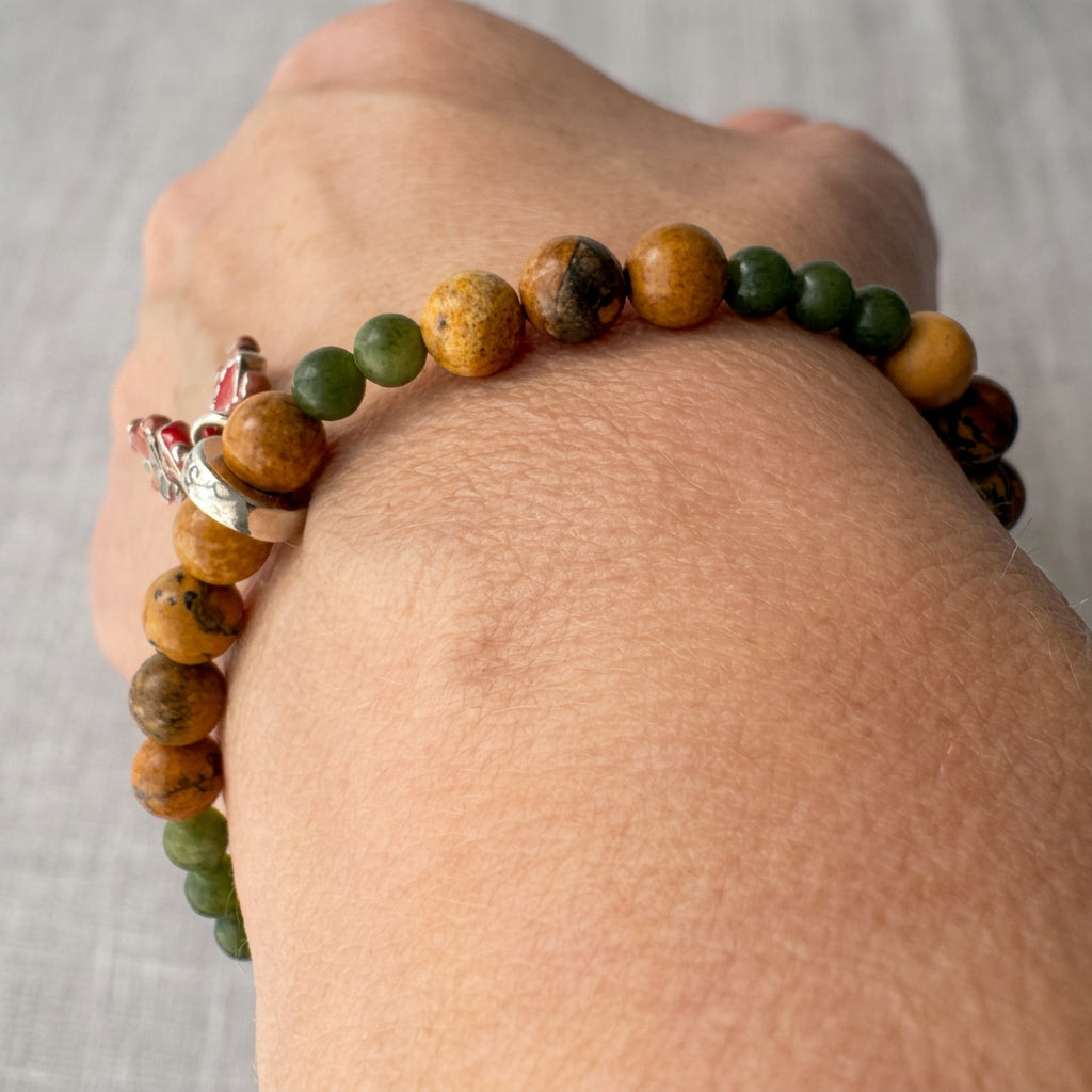 Picture jasper and green jade bracelet worn on a wrist, showing mottled golden-brown beads interspersed with smaller green beads.