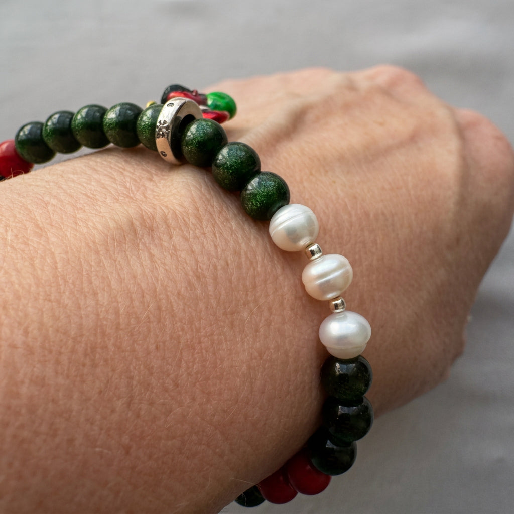 Green sandstone bracelet worn on a wrist, showing three white pearls separated by silver-coloured spacers and red coral accents.