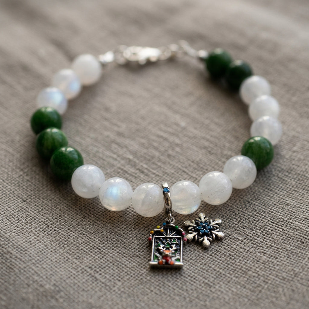 White and green jade bracelet with blue crystal snowflake and reindeer Advent door charms, arranged on grey linen.