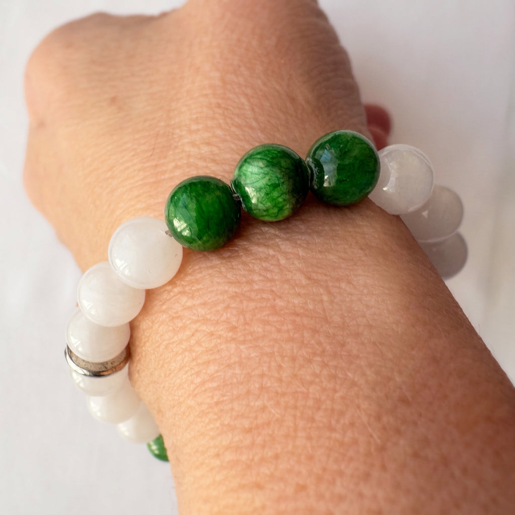 White and green jade bracelet worn on a wrist, showing three translucent green beads between milky white beads.