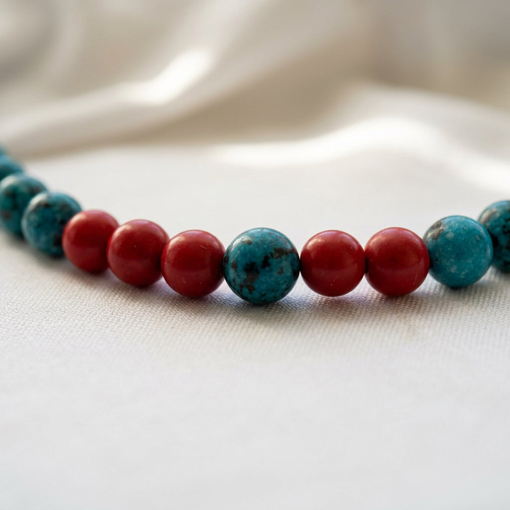 Close-up of mottled blue agate beads interspersed with glossy red coral beads on cream fabric.