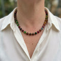 Blue jasper, carnelian, yellow topaz and white pearl necklace worn with an open-neck white shirt, showing mottled blue-green beads, rich orange-red stones, bright yellow accents and small gold-coloured spacers.