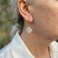 White square baroque pearl drop earring worn on an ear, hanging diagonally from a gold-filled hook and connecting links with a soft iridescent sheen.