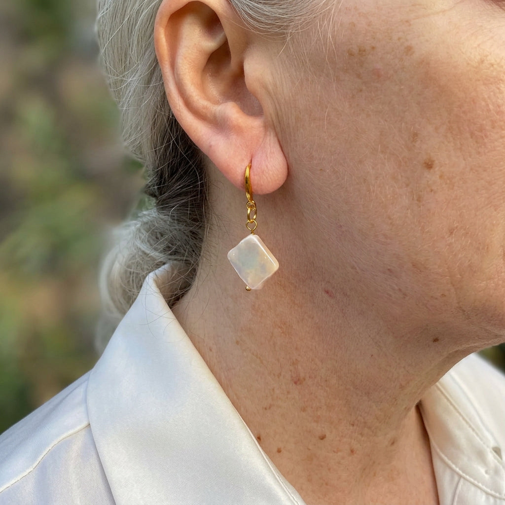 White square baroque pearl drop earring worn on an ear, hanging diagonally from a gold-filled hook and connecting links with a soft iridescent sheen.