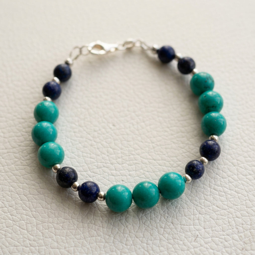Lapis lazuli and stabilised Hubei turquoise bracelet arranged in an oval on a white textured surface, with a sterling silver clasp.