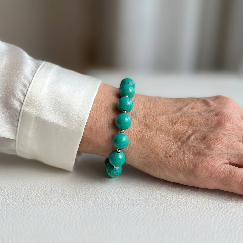 Hubei turquoise bracelet with sterling silver beads worn on the wrist beside a white cuff.