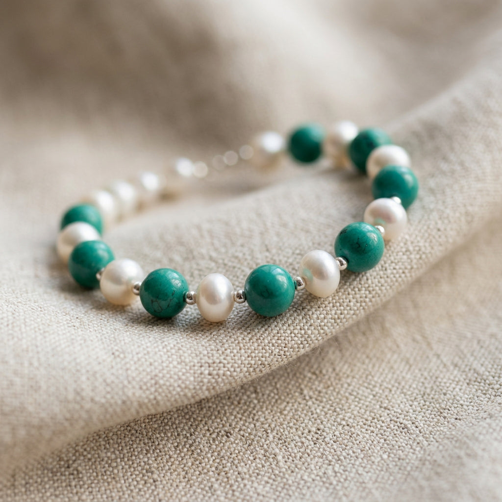 Hubei turquoise and white baroque pearl bracelet arranged on cream linen with sterling silver beads between the stones and pearls.