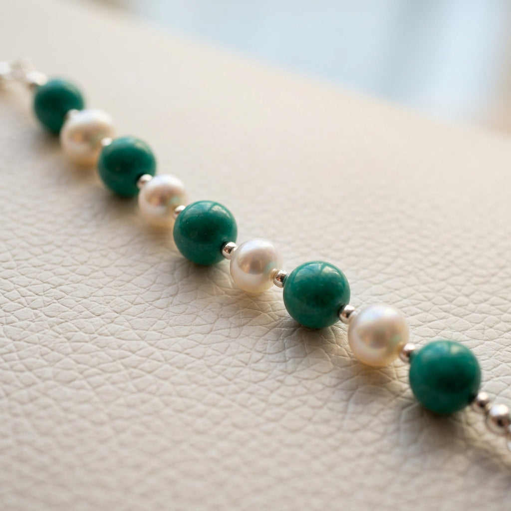 Hubei turquoise and white baroque pearls running diagonally across a white textured surface, with sterling silver beads between them.