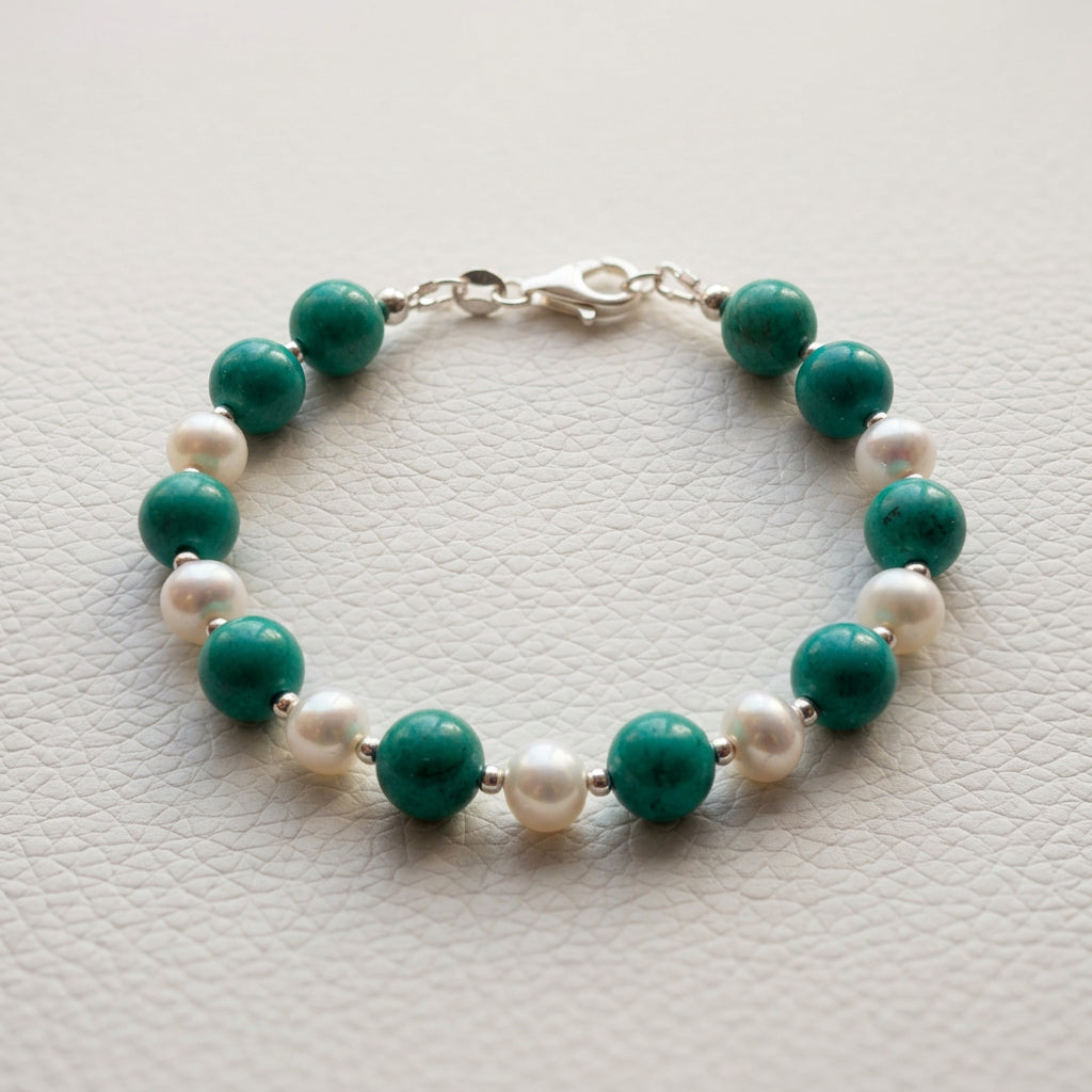 Full view of Hubei turquoise and white baroque pearl bracelet on a white textured surface, showing the sterling silver clasp.