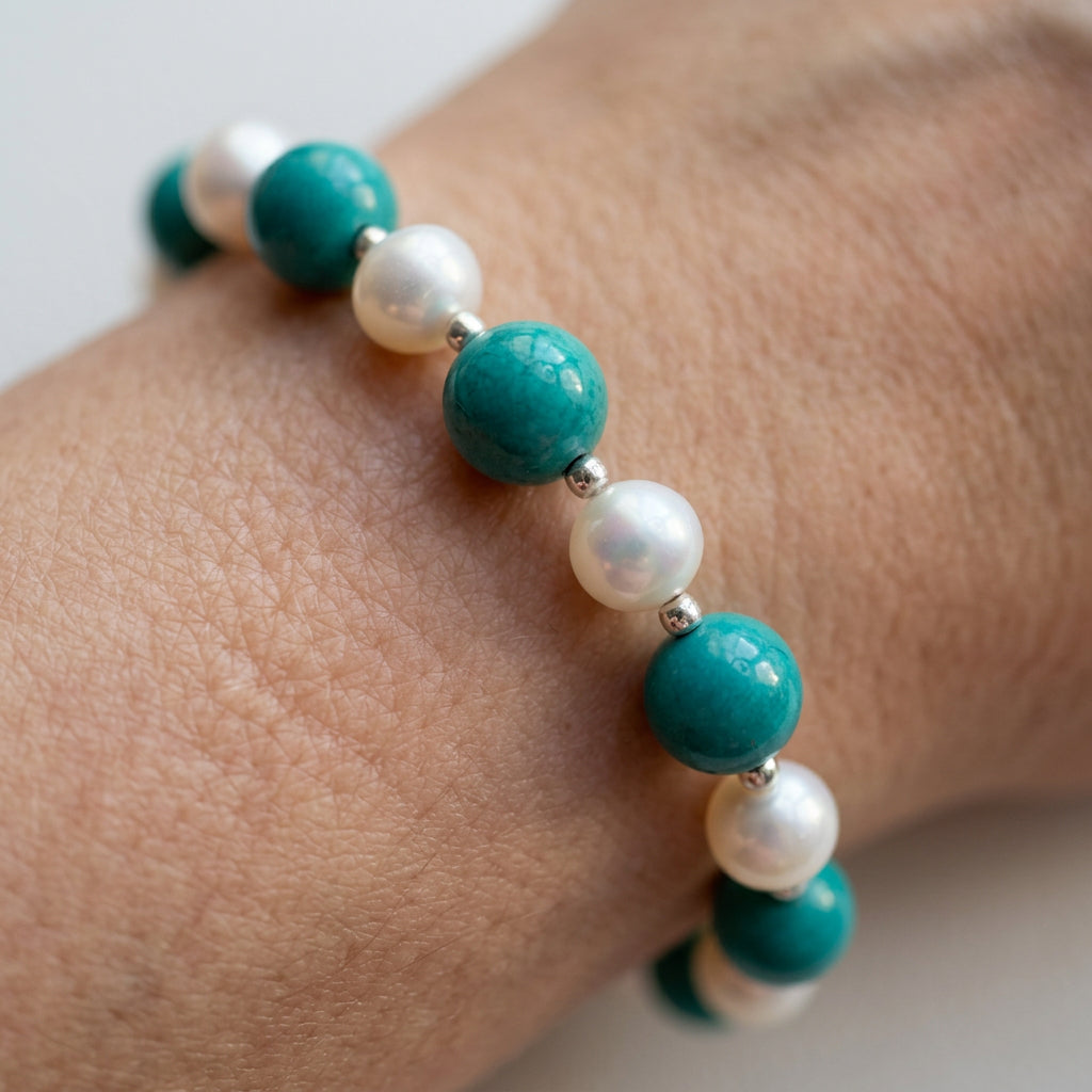 Close-up of green-blue Hubei turquoise, white baroque pearls and sterling silver beads on the wrist.