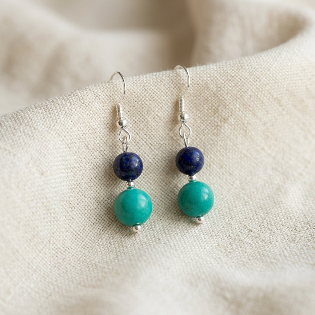 Lapis lazuli and Hubei turquoise drop earrings with sterling silver hooks resting together on softly folded cream linen.