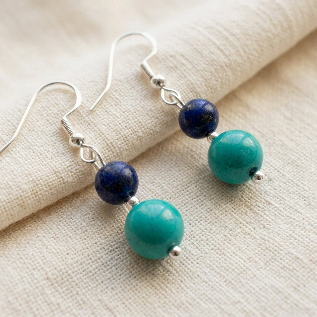 Pair of lapis lazuli and Hubei turquoise drop earrings with sterling silver hooks on folded cream linen.