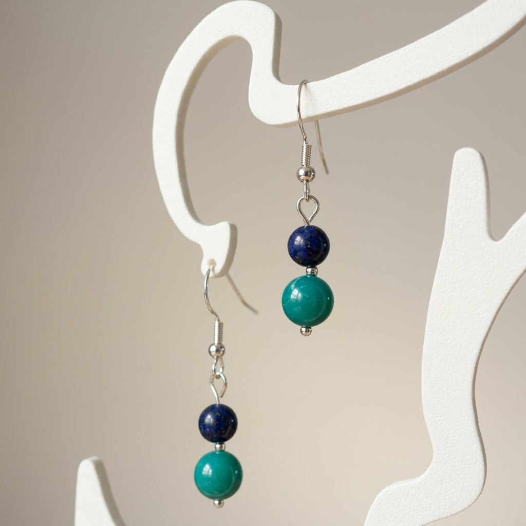 Lapis lazuli and Hubei turquoise drop earrings hanging from a cream display stand on sterling silver hooks.