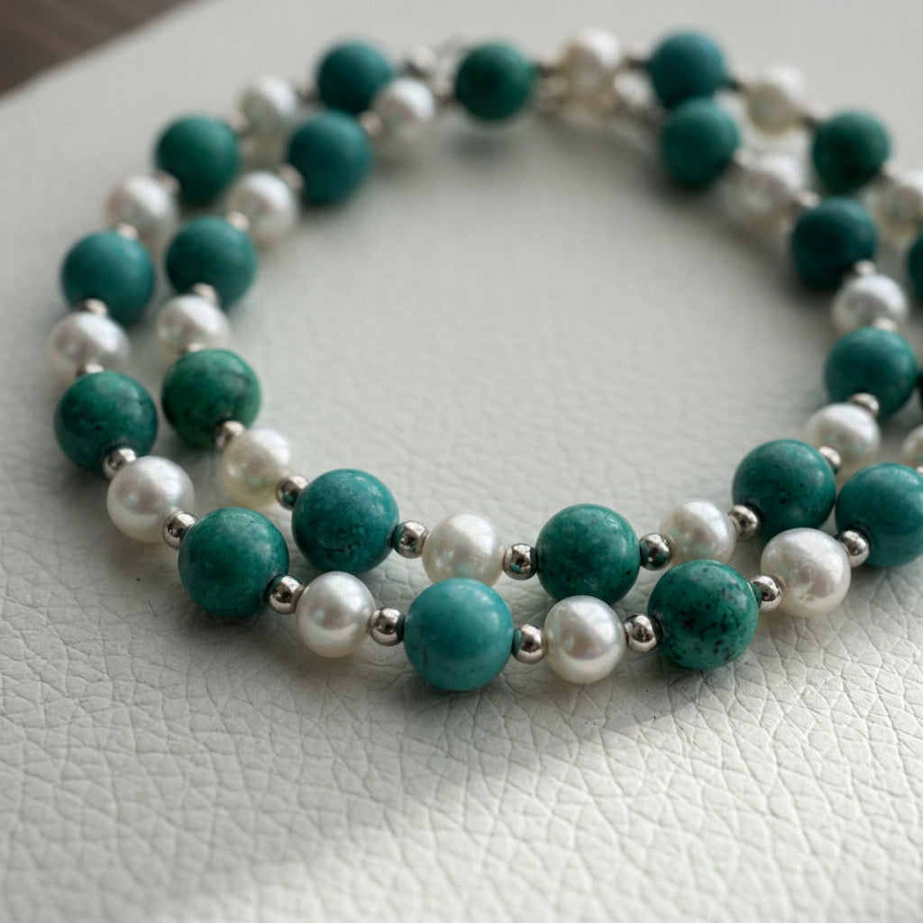 Hubei turquoise and white baroque pearl necklace arranged in overlapping loops on a white textured surface.