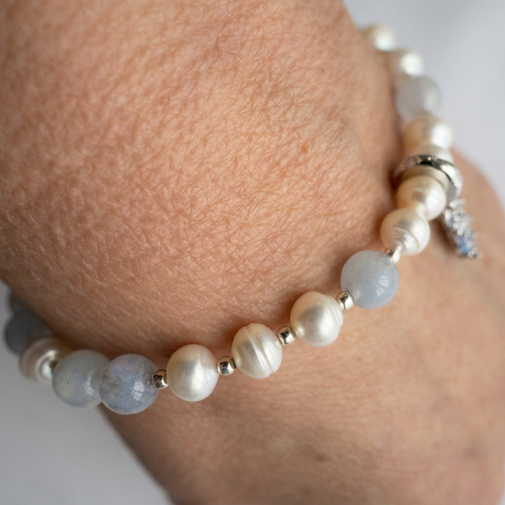 Aquamarine and white baroque pearl bracelet worn close up, showing sterling silver fittings and a crystal snowflake charm.