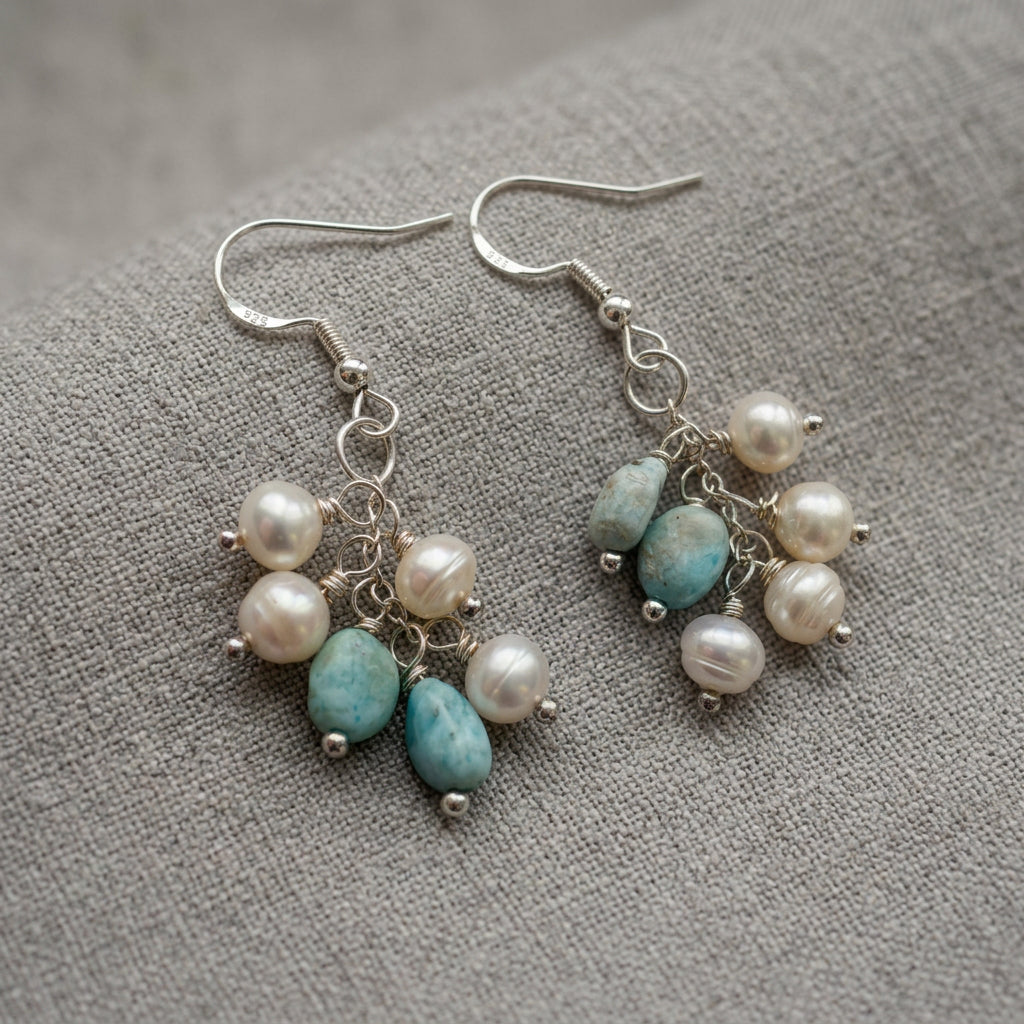 Pair of sterling silver cluster drop earrings on grey linen, each featuring four white baroque pearls and two pale blue larimar stones suspended from wire-wrapped links.