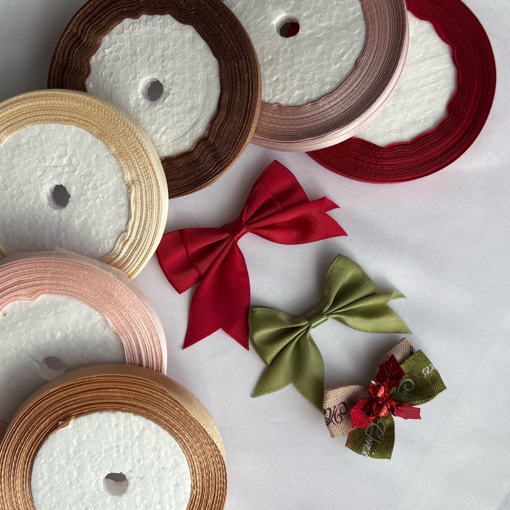 Satin ribbon rolls and decorative bows in red, green, pink, cream and gold for Pearl Art Nature gift packaging.