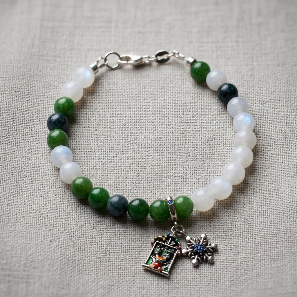 White and green jade bracelet with blue tourmaline, snowflake and Advent window charms, arranged on beige linen.
