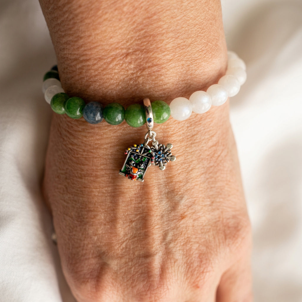 White and green jade bracelet with blue tourmaline, worn on a wrist with reindeer Advent window and snowflake charms.