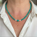 Hubei turquoise necklace worn with a white collared shirt, showing a larger central turquoise bead between two white baroque pearls.