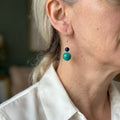 Sterling silver drop earring worn on the ear, with dark blue lapis lazuli above a larger green-blue Hubei turquoise bead.