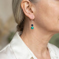 Sterling silver drop earring worn on the ear, with a small dark blue lapis lazuli bead above green-blue Hubei turquoise.