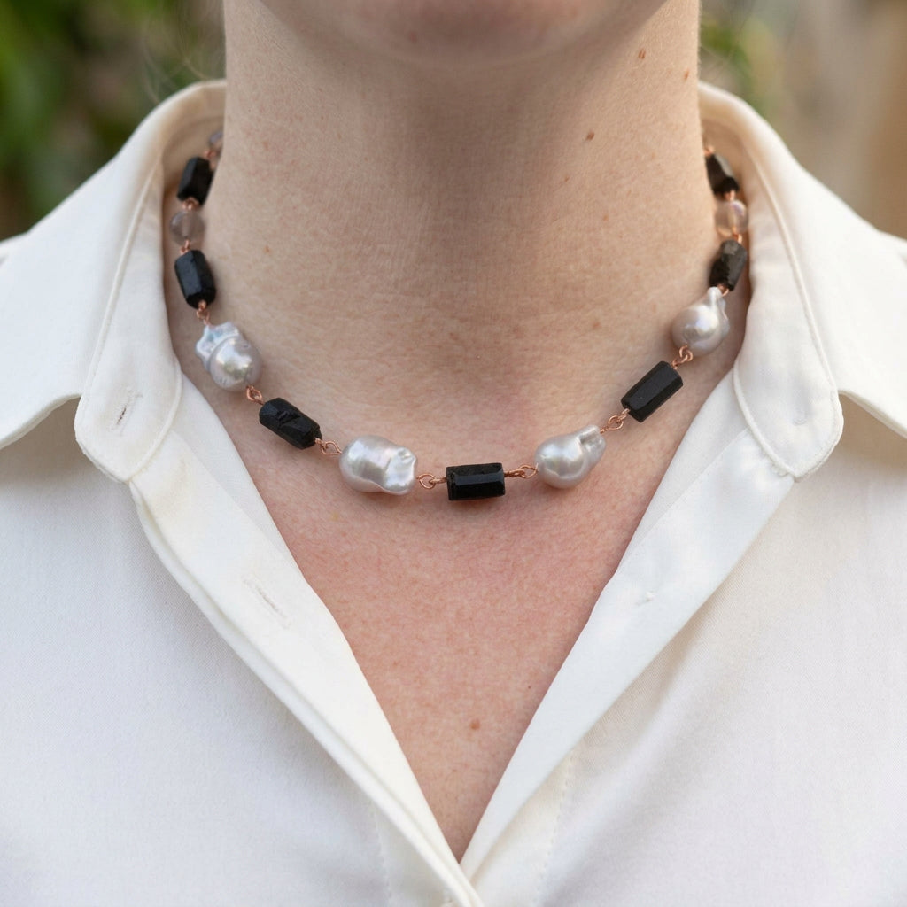 Silver keshi pearl, raw black tourmaline and labradorite necklace worn with an open-neck white shirt, showing four large irregular lustrous pearls, rough black crystals and pale grey beads joined by handmade copper wire links.