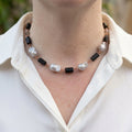 Silver keshi pearl, raw black tourmaline and labradorite necklace worn with an open-neck white shirt, showing four large irregular lustrous pearls, rough black crystals and pale grey beads joined by handmade copper wire links.