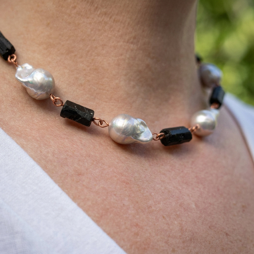 Side view of a necklace worn at the collarbone, showing large silver Keshi pearls and raw black tourmaline crystals joined by copper wire links.