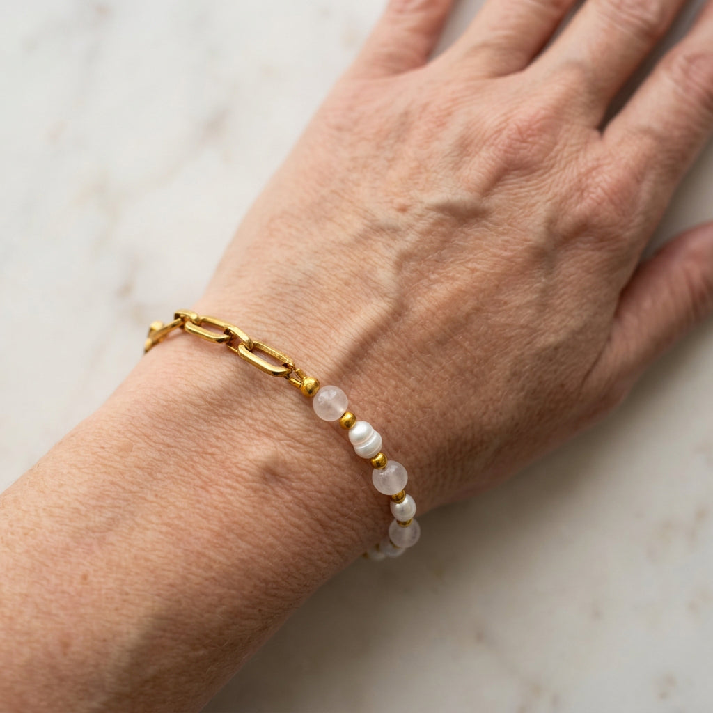 Pink quartz and white baroque pearl bracelet worn on a wrist, showing alternating beads with gold-coloured spacers meeting a gold-plated paperclip chain.
